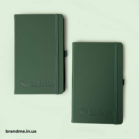 Пара темно зелених блокнотів з тисненим логотипом, що підкреслюють статус і надихають на нові проєкти