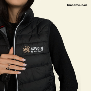 Вишитий логотип Savory на чорній стьобаній жилетці — брендування одягу