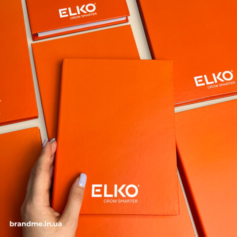 Помаранчевий брендований блокнот ELKO з логотипом на обкладинці для корпоративного використання.
