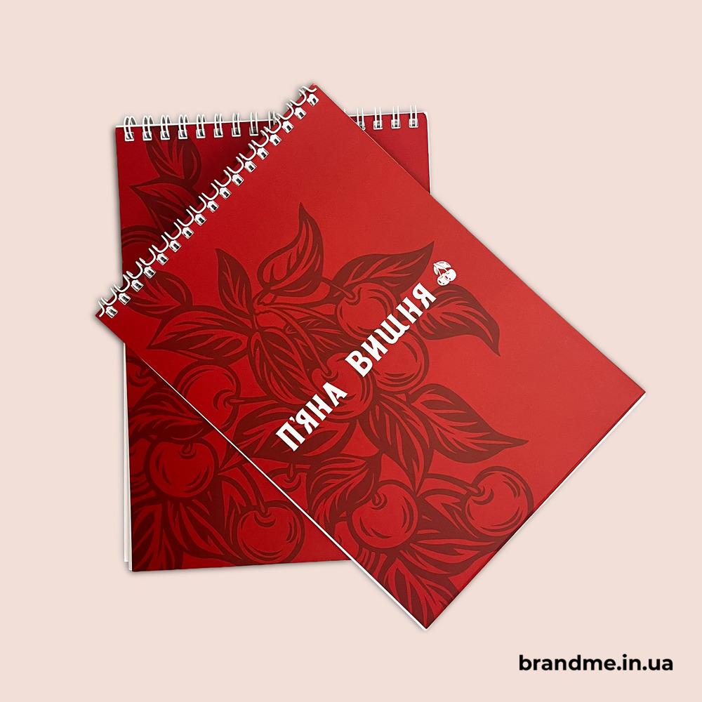 Корпоративна канцелярія: що замовити для команди та офісу. Фото 1 | BRANDME Червоні брендовані блокноти «П’яна Вишня» на пружині з логотипом і фірмовим дизайном обкладинки.